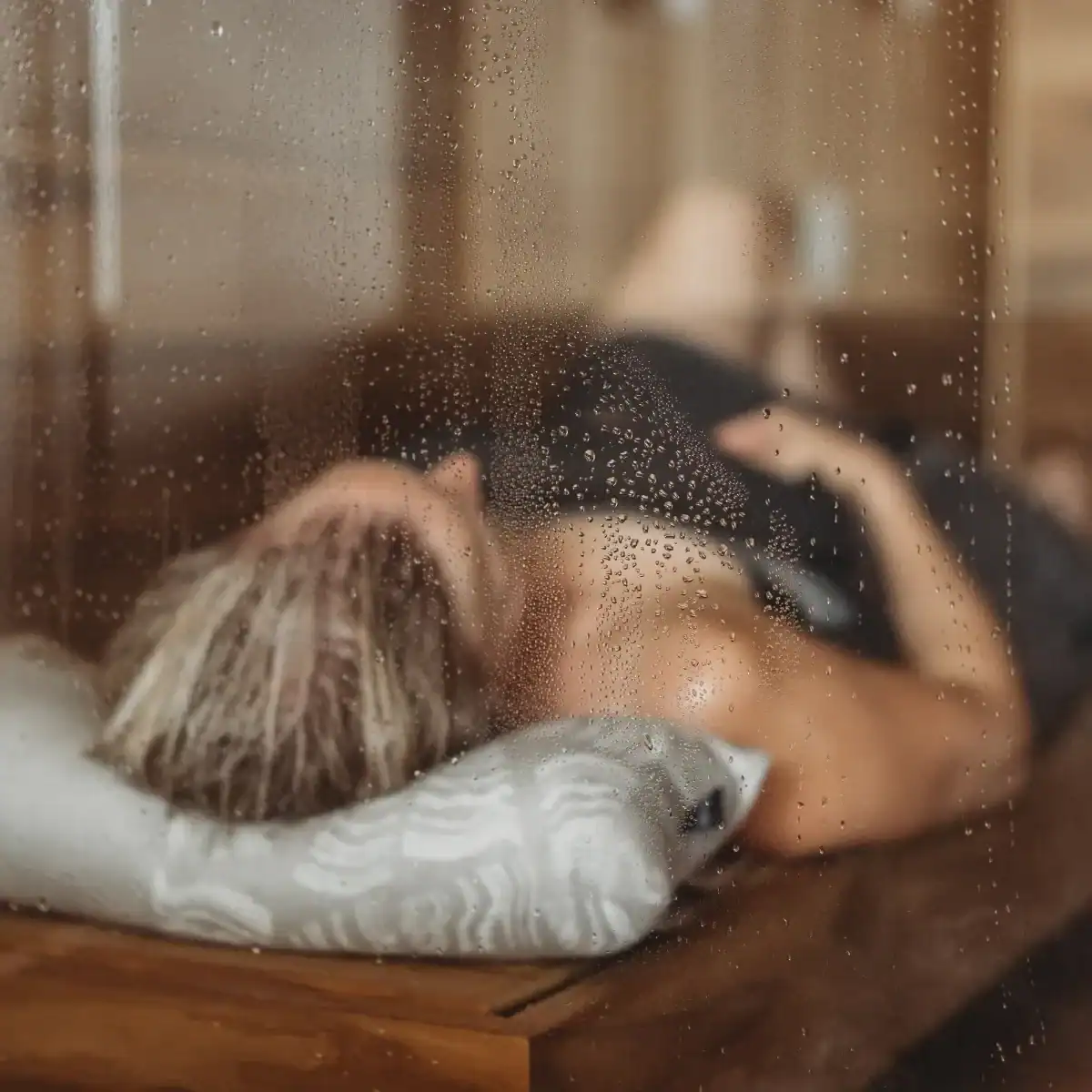 Swimmer lies relaxed on a sauna cushion, enjoying rest and warmth in the sauna. Perfect for comfort.