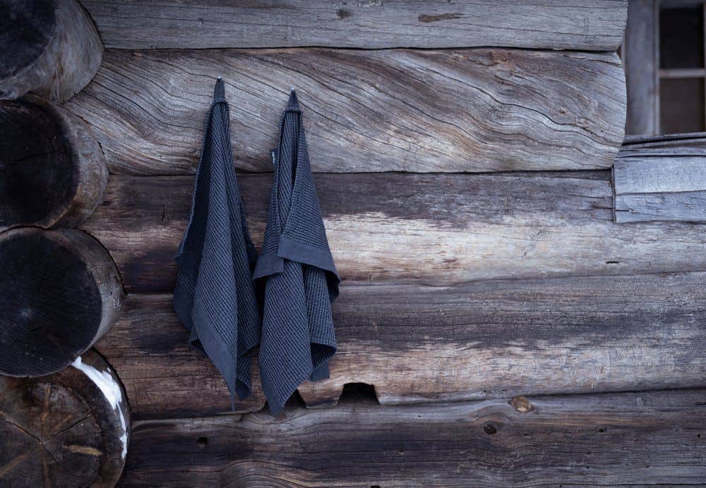 Grey Rento sauna towel of 50x70 cm, hanging on a wooden wall.