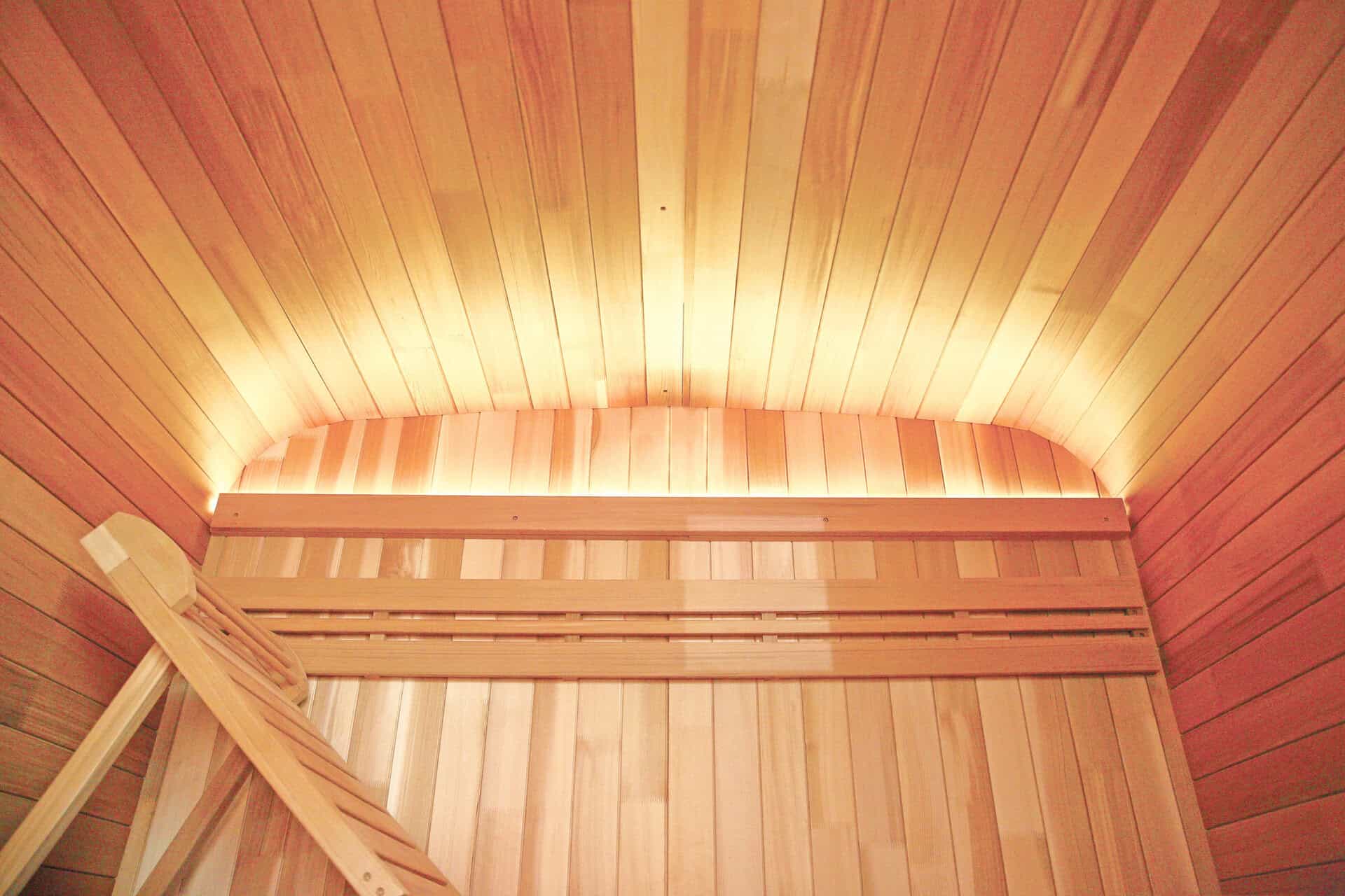 Wooden outdoor sauna with wooden interior and atmospheric lighting.