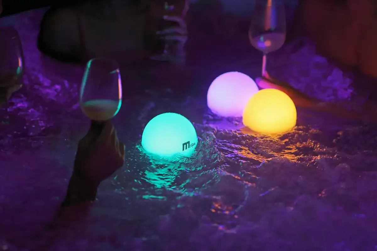 Floating LED swim lamps in a pool with colourful light.