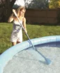 Child using a pool vacuum cleaner to clean the pool.